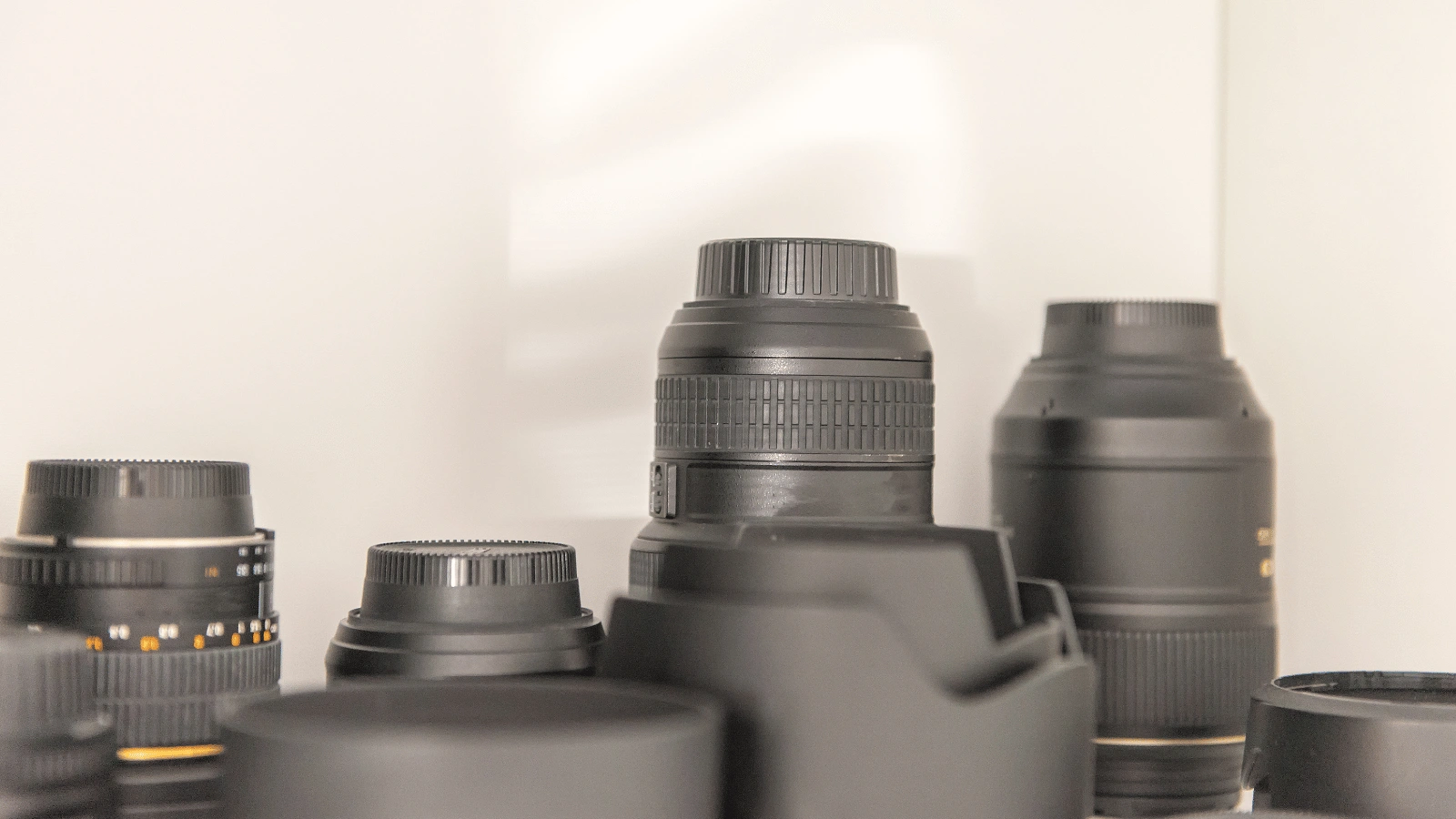 Assortment of camera lenses arranged for taking action shots for sporting goods on a plain background.