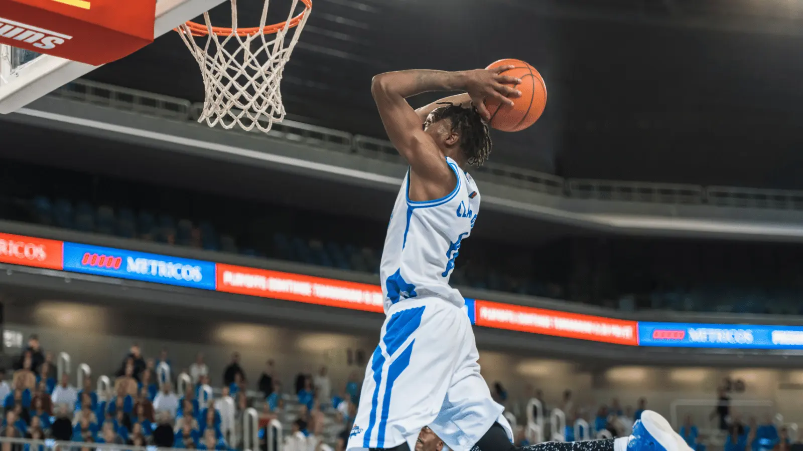 Basketball player shooting in an arena with a crowd for dynamic sports marketing examples of action and engagement.